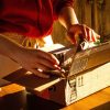 A woman opens a plain cardboard box on her kitchen counter to test a new product.