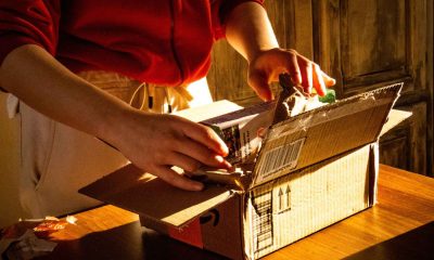 A woman opens a plain cardboard box on her kitchen counter to test a new product.